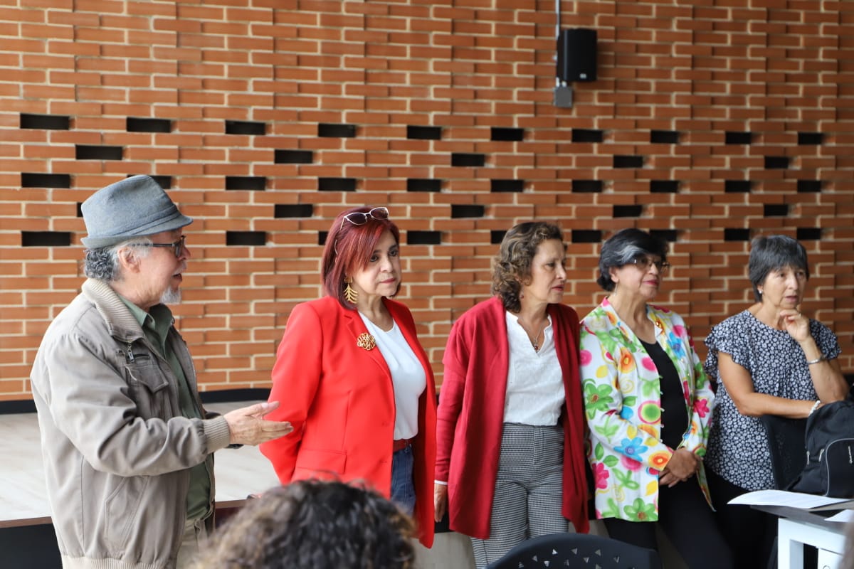 Foto de 5 profesoras y un profesor hablando al frente del auditorio