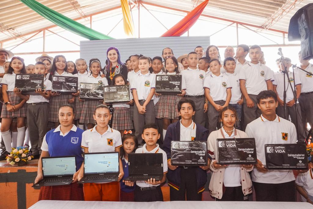 Foto de la Profe Sindey Carolina Bernal, junto a varios estudiantes recibiendo computadoras