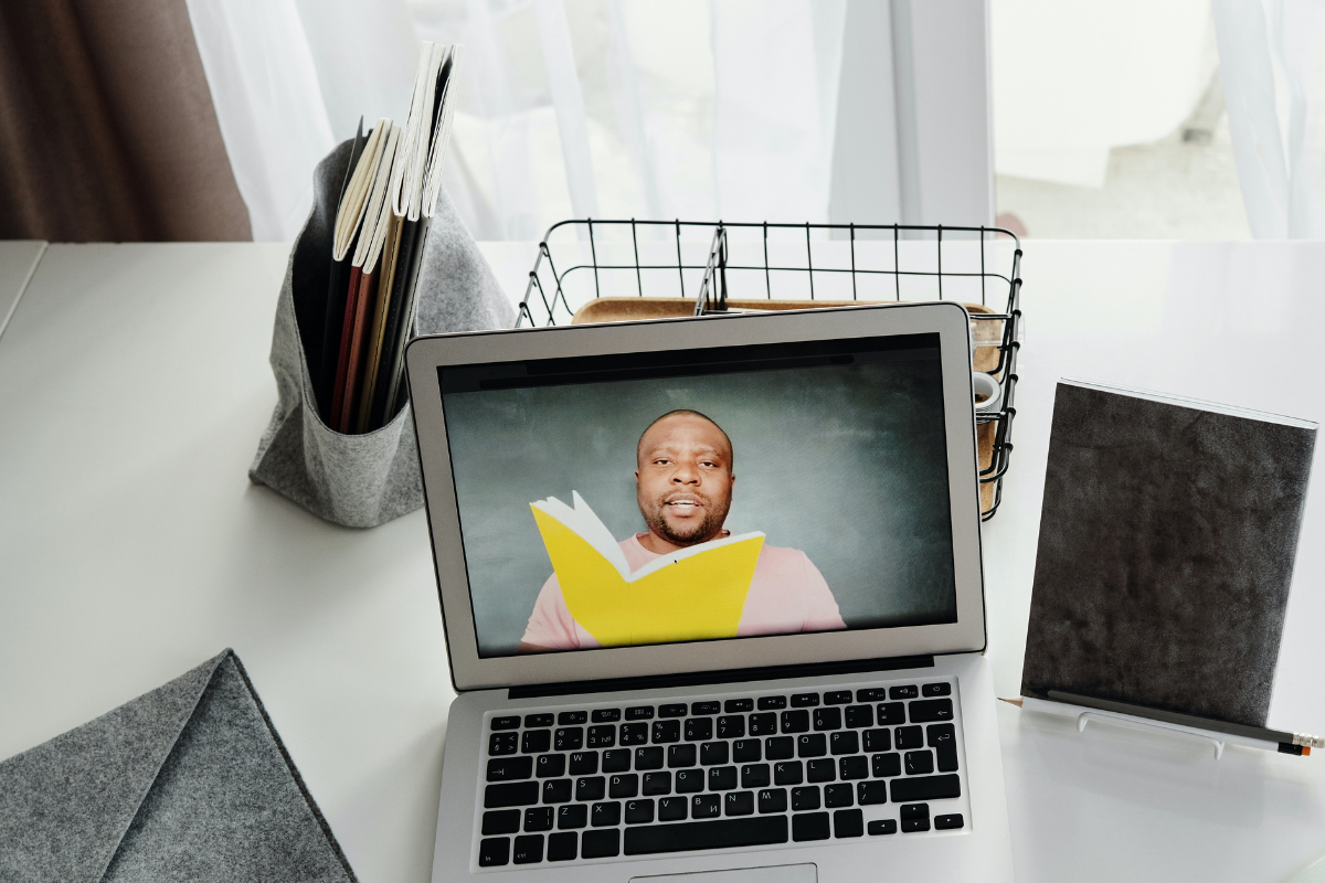 Imagen de un portátil y un hombre en la pantalla leyendo