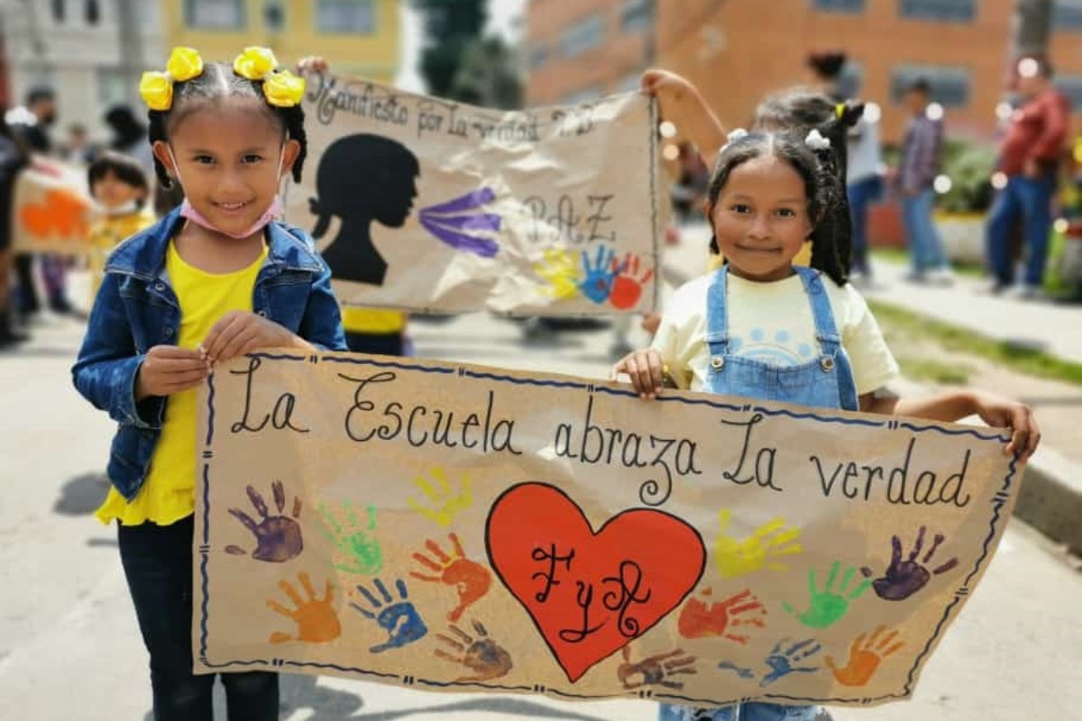 Imagen de un aula de clase con varios estudiantes y la foto del profesor José Antequera Guzmán