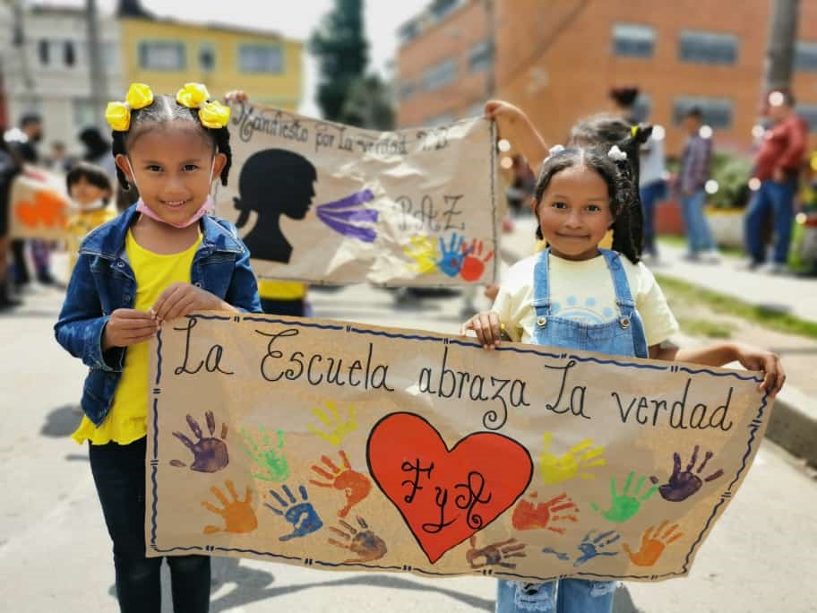 Dos niñas sosteniendo una pancarta que dice La escuela abraza la verdad