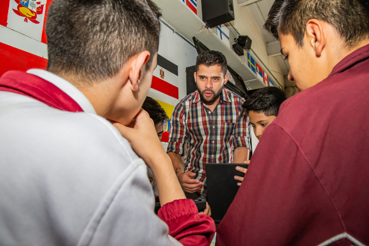 Imagen de un aula de clase con varios estudiantes y la foto del profesor José Antequera Guzmán
