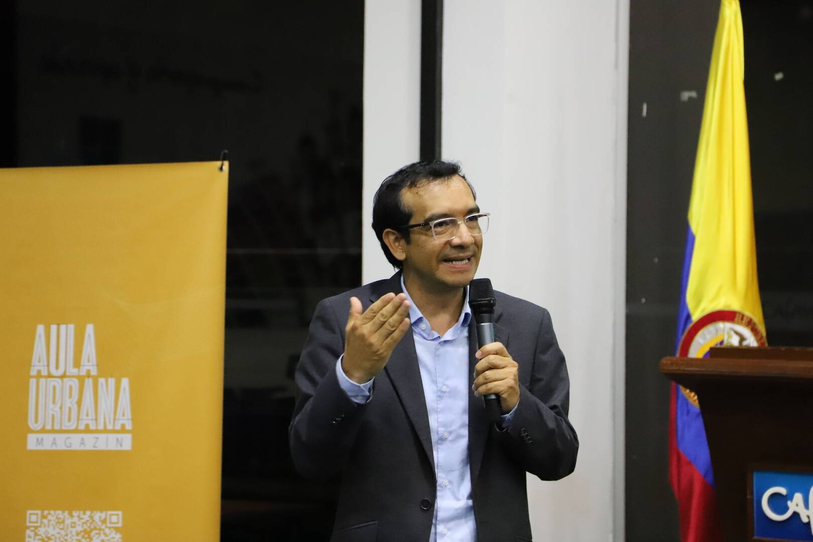 Imagen de un aula de clase con varios estudiantes y la foto del profesor José Antequera Guzmán