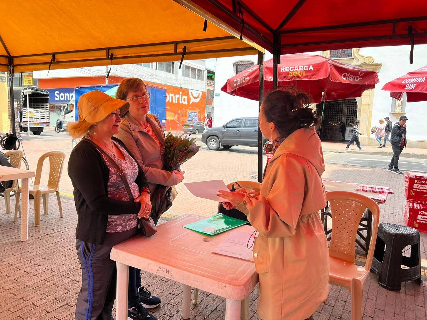 Funcionaria del IDEP explicando a dos ciudadanas como participar en el Plan de Desarrollo Distrital